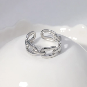 Detailed view of silver titanium steel chain link ring on white ceramic stand