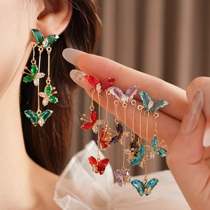 Détail des boucles d'oreilles pampilles dorées avec breloques papillons en zircon
