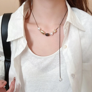 Macro shot of tiger eye stone and pearl flower pendant necklace on a black cord
