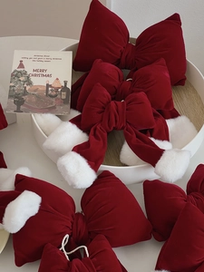 Close-up of red velvet Christmas bow with white pompoms on a festive display tray