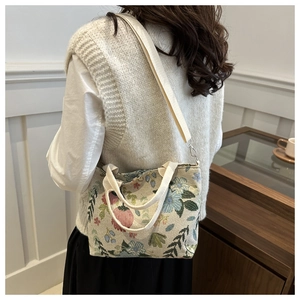 Detailed back view of a chic floral tapestry shoulder bag with adjustable cream straps