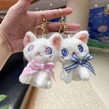 Close-up of white plush cat keychains with pink and blue plaid bows and starry eyes