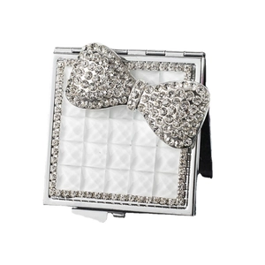 Square silver folding mirror with white quilted texture and sparkling rhinestone bow