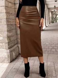 Detail of a brown faux leather midi skirt with side pleats shown in an outdoor setting