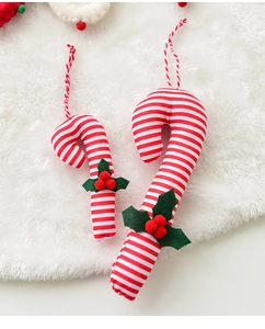 Detail of red and white striped fabric candy canes with green leaves on a white faux fur rug
