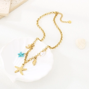 Detailed shot of golden starfish and seashell pendants on a necklace in a shell tray