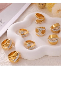 Detalle de anillos dorados con diseño cruzado e incrustaciones de cristal en bandeja