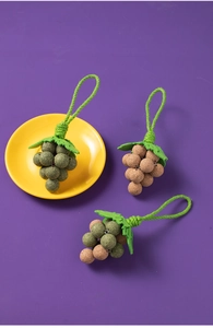 Detailed view of grape-shaped catnip chew toys with green leaves on a vibrant purple backdrop