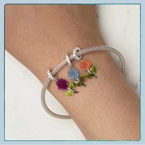 Macro detail of S925 silver mesh bracelet with colorful rose charms on a female wrist