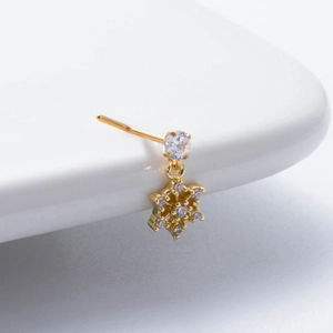 Macro shot of gold-plated snowflake nose stud with sparkling zircon gemstones