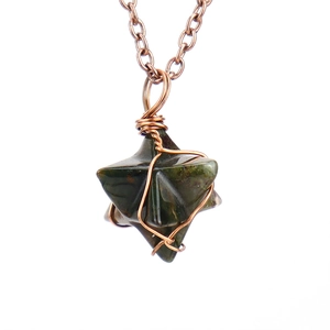 Detailed view of hand-wrapped copper wire on a Merkabah green agate stone pendant