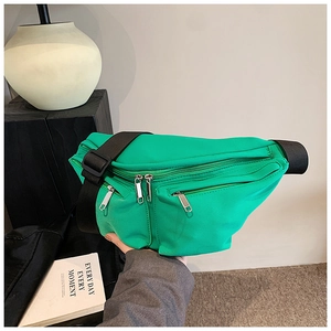 Close-up of vibrant green nylon crossbody bag with black strap and silver metal zippers