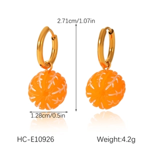 Macro shot of stainless steel gold hoops with orange fruit pendants and size indicators