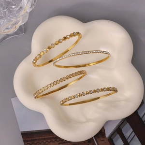 Dettaglio di quattro bracciali dorati di lusso con cuori di cristallo e pavé