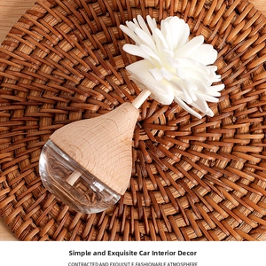 Detail of glass diffuser bottle with wooden cap and white flower on rattan tray