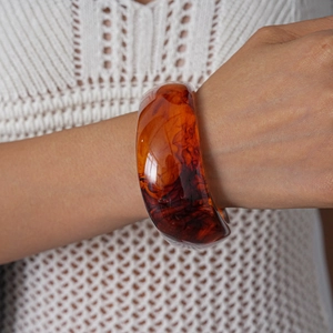 Close-up of amber texture resin bangle with irregular geometric patterns on a model's wrist
