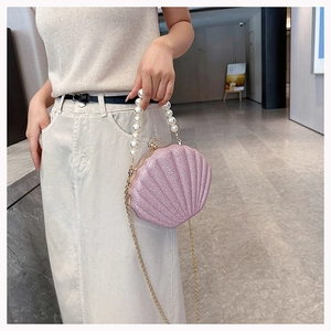 Pink shell-shaped evening bag with pearl handle and golden chain strap in close-up shot