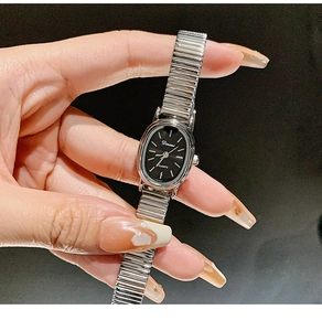Macro shot of silver quartz watch with oval black dial and elastic metal strap