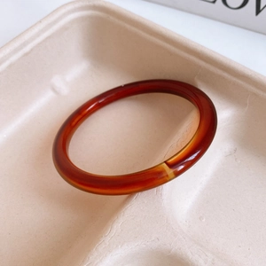 Detailed view of a translucent reddish-brown resin bangle with glossy jelly-like texture