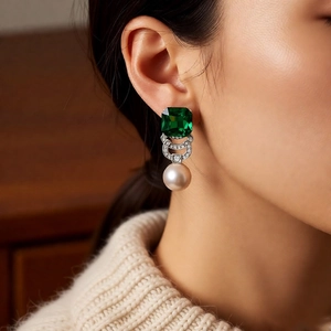 Close-up of vintage square emerald and pearl drop earrings worn by a model