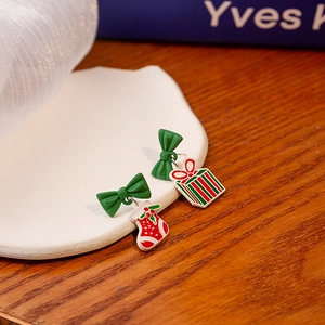 Detailed macro view of asymmetric Christmas earrings with red stocking and gift box charms