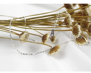 Macro detail of S925 sterling silver barrel-shaped pendant necklace on brown dried flowers