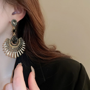 Gros plan de boucles d'oreilles vintage en forme d'éventail doré sur un mannequin