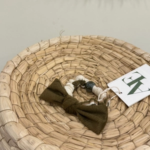 Dark green bow hair scrunchie with striped elastic band and bead detail on woven basket
