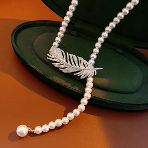 Detail of a luxury pearl necklace with a zircon-set feather pendant in a velvet box