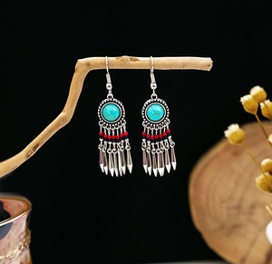 Detailed view of Bohemian turquoise earrings with ethnic metal tassels on wood
