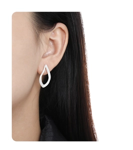 Detail of silver irregular geometric stud earrings worn on ear showing high metal luster