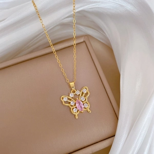 Gold hollow butterfly necklace with sparkling crystals and pink gem on silk background
