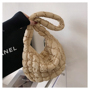 Detailed macro view of beige quilted cloud bag texture with smooth metal zipper closure