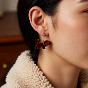 Detail of brown flocked puppy earring with silver beads and heart zircon on model