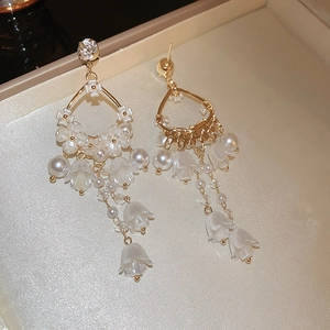 Detail of elegant gold flower earrings with white petals, pearls and crystals