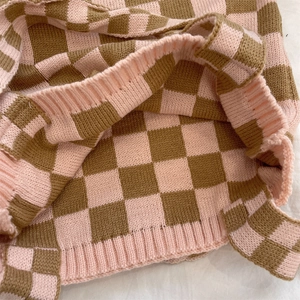 Detailed close-up of pink and brown checkered knit fabric with ribbed edge texture
