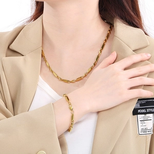 Ensemble collier et bracelet minimaliste en acier titane doré porté par mannequin