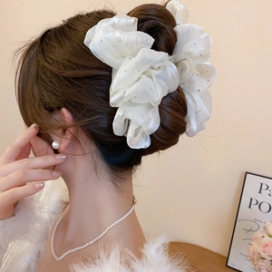 Detail view of large white mesh bow hair claw with sparkling rhinestones on hair