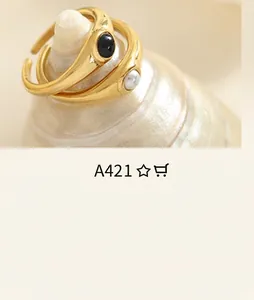 Detail of adjustable gold-plated ring set featuring a black gem and a freshwater pearl