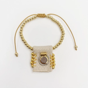 Detailed close-up of handmade woven Saint Benedict medal bracelet with golden metal beads