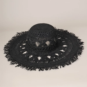 Primo piano del cappello da spiaggia in paglia nera intrecciata con frange