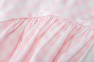 Detail of pink and white gingham fabric with intricate pleated stitching on dress