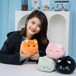 Cute round cat plush toy doll in orange color held by model against a cozy background
