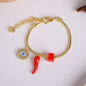 Detail of 18K gold snake chain bracelet with evil eye and red chili pepper charms