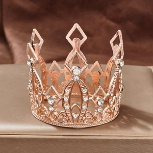 Macro view of rose gold alloy mini crown with sparkling rhinestones on gold stand