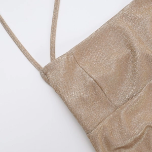 Macro view of metallic gold glitter fabric and delicate strap stitching on the dress