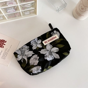 Detail of floral relief pouch with black base and white flower prints on a white table