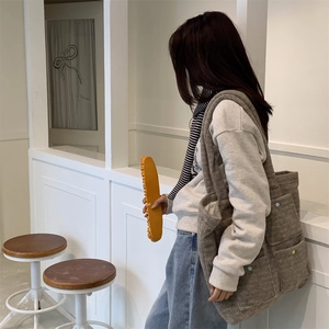 Detail of grey plush tote bag featuring three front pockets and colorful buttons