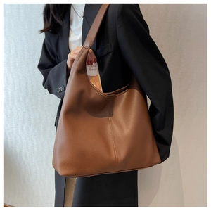 Brown large capacity tote bag worn by model in black blazer for elegant commute look