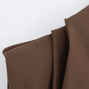 Detailed macro shot of deep brown ruched fabric texture and fine pleated shoulder seam